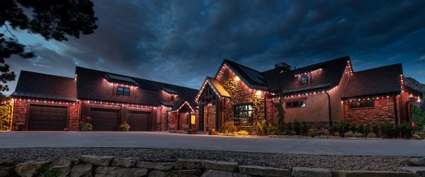 A cozy house illuminated with warm lights against a dramatic evening sky.